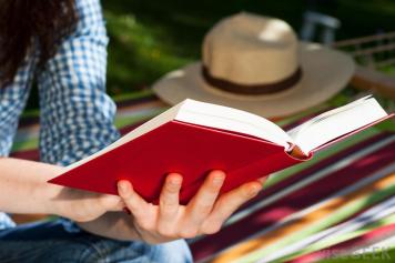 person-reading-red-covered-book-near-grass.jpg