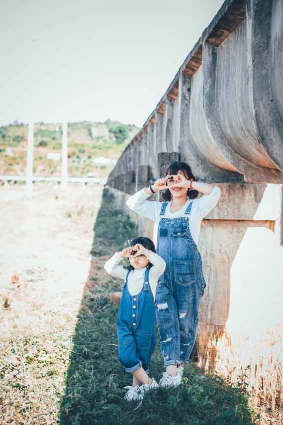 two girls standing beside concrete wall