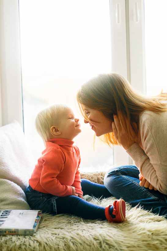 woman and child sitting on fur covered bed