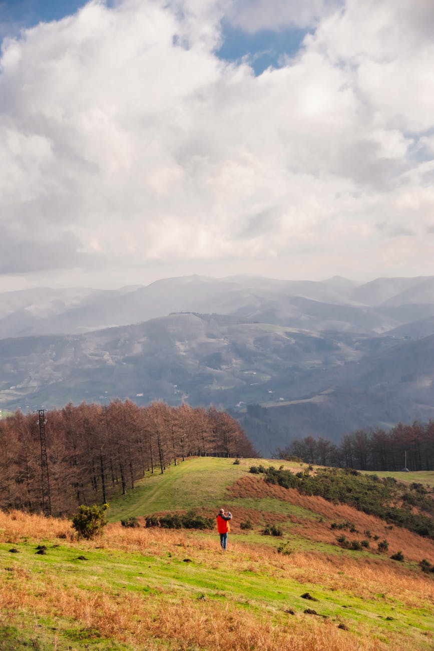 lonely traveler on hillside under cloudy sky