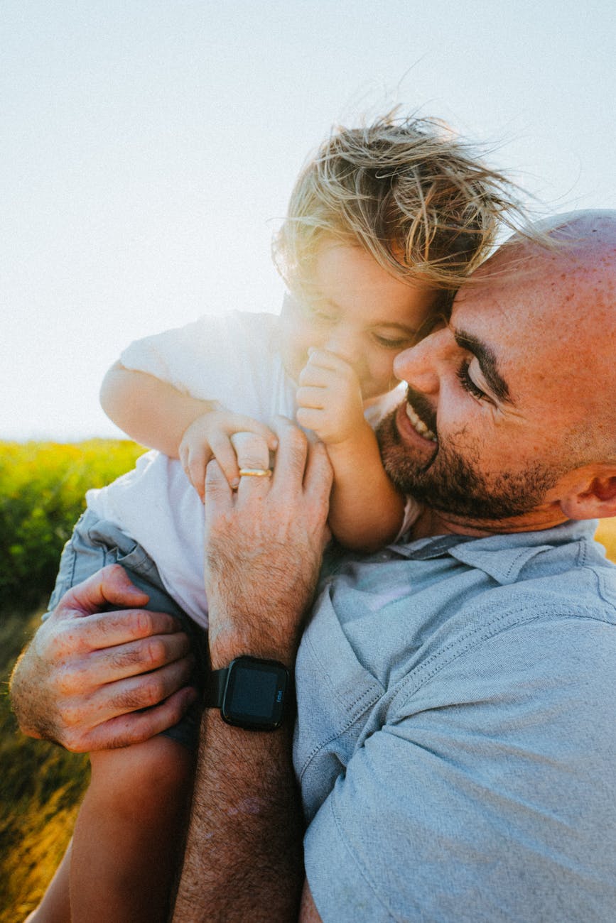 cheerful father carrying little son in lush nature